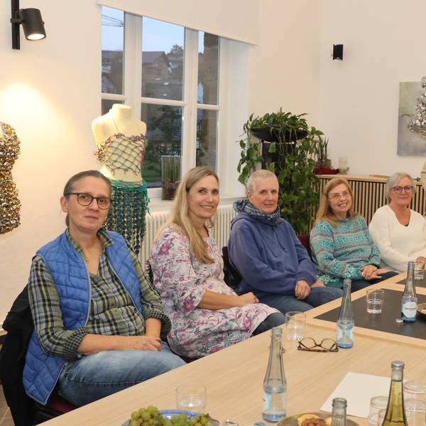 Zu sehen sind Künstlerinnen und Künstler an einem langen Tisch.