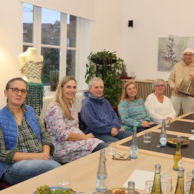 Zu sehen sind Künstlerinnen und Künstler an einem langen Tisch.