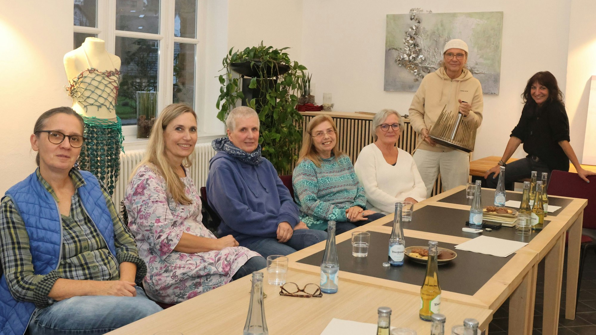 Zu sehen sind Künstlerinnen und Künstler an einem langen Tisch.