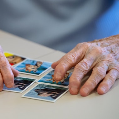 Eine Bewohnerin eines Altenheims spielt auf einer Pflegestation das Spiel „Memory“und legt Kartenpaare zusammen.