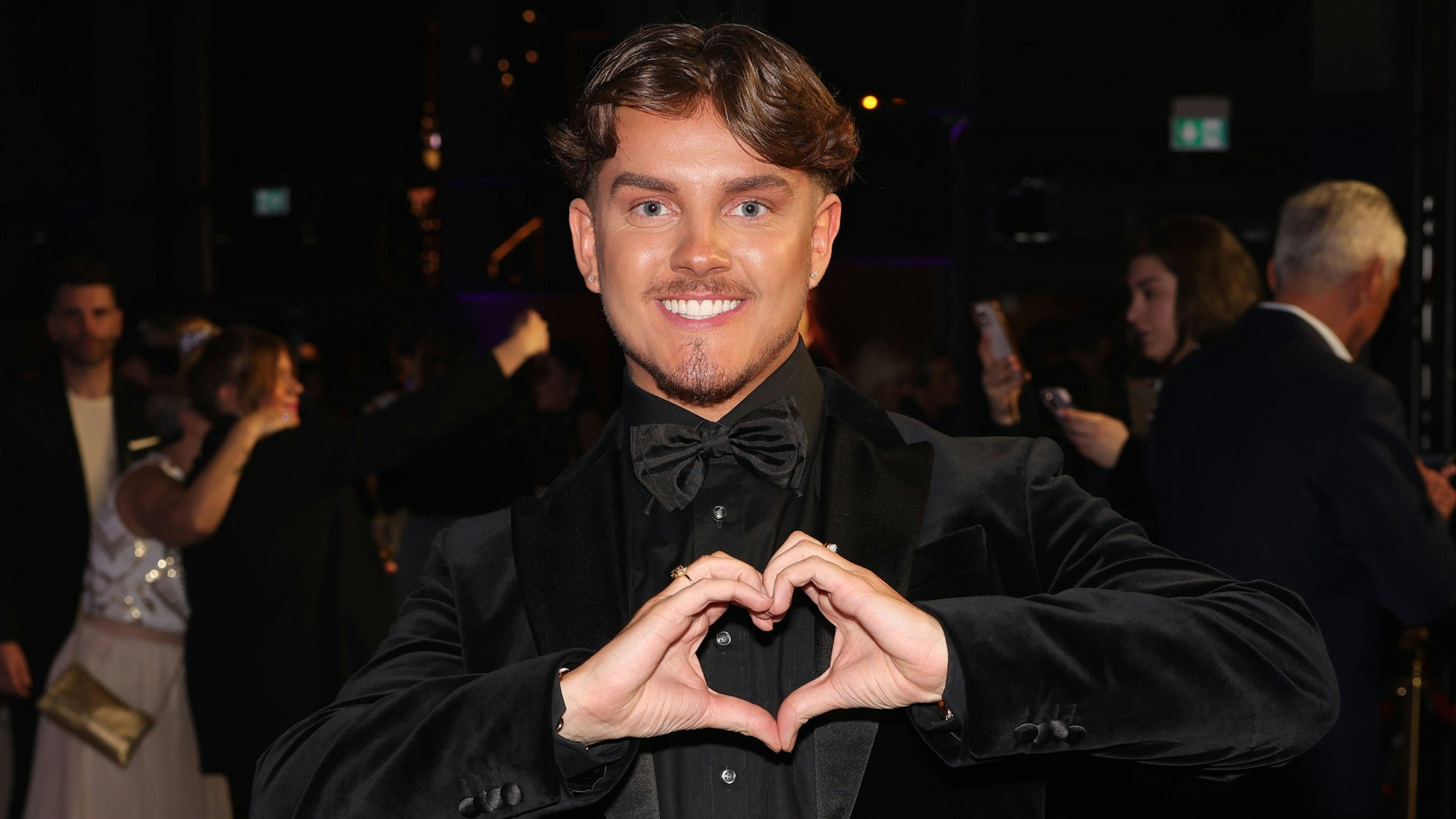 Twenty4Tim formt mit seinen Händen ein Herz.