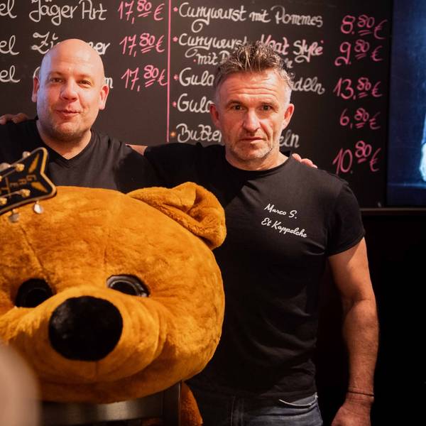 Das Bild zeigt die drei Organisatoren, die sich in den Arm nehmen. Vor Jörg Peter liegt ein überdimensionaler Plüschbärenkopf.