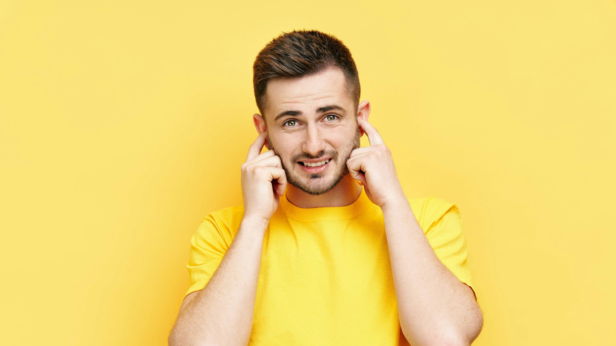 Ein Mann hält sich mit den Zeigefingern die Ohren