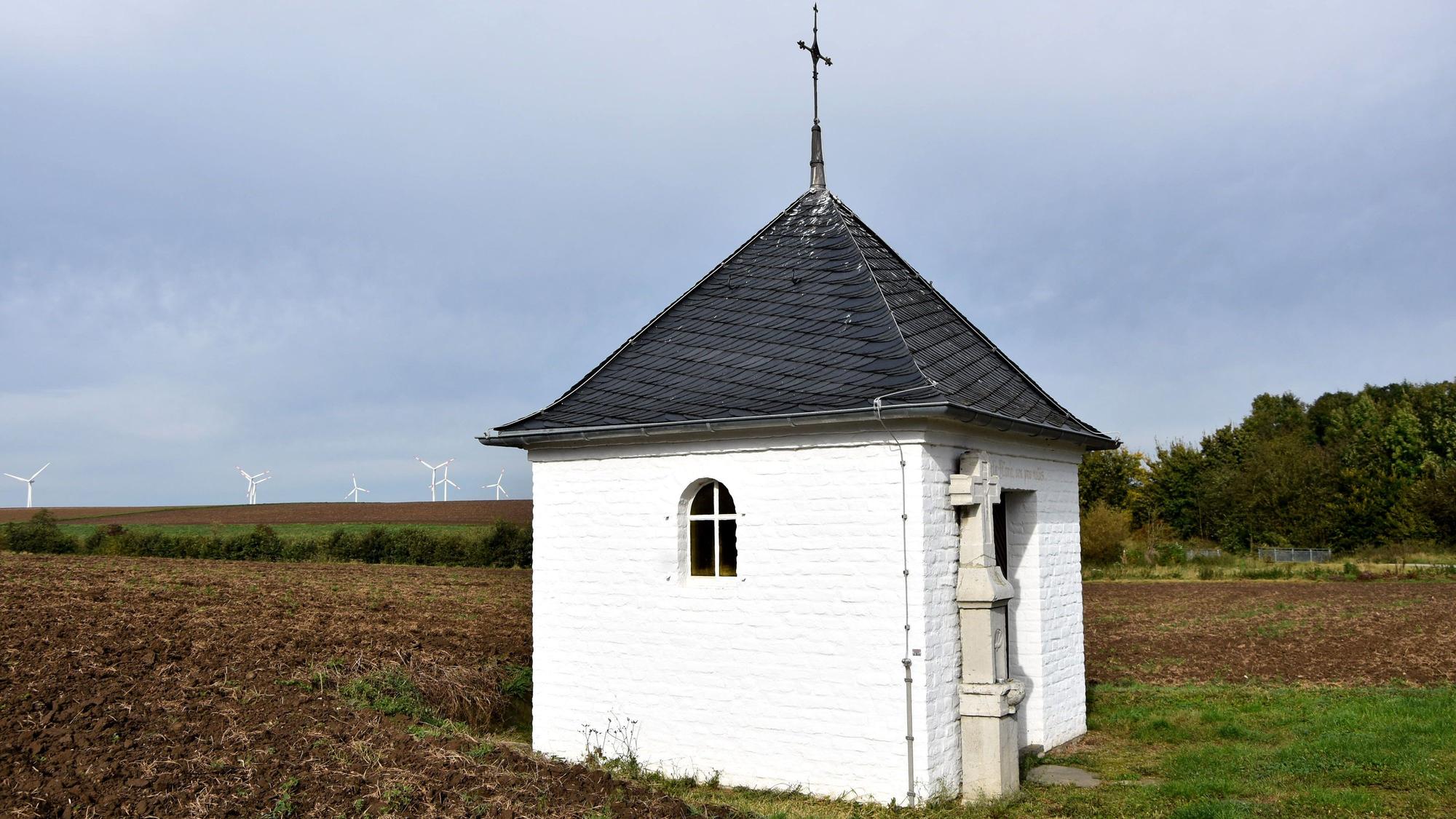 Eine kleine weiße Kapelle steht auf einem Feld.