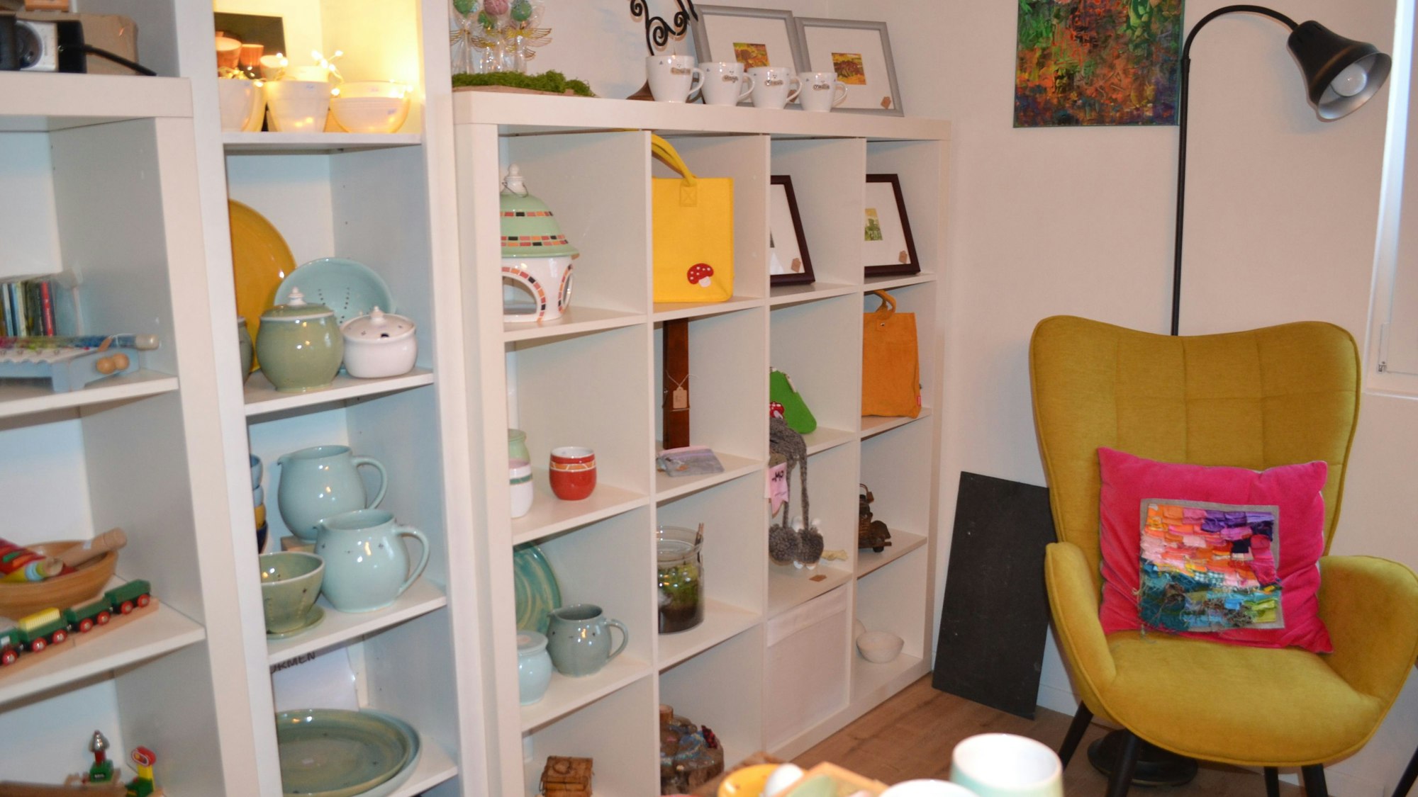 Ein Regal mit Porzellan, daneben ein Sessel mit Lampe.