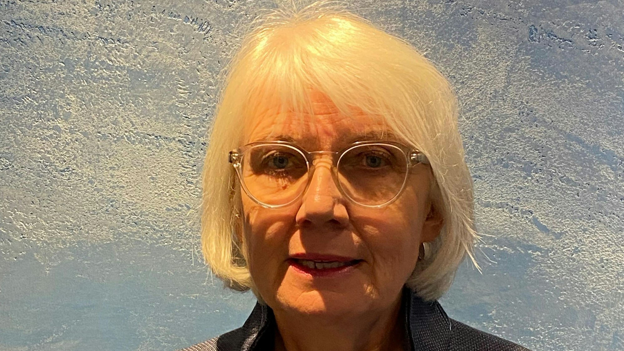 Die Preisträgerin, sie hat weiße Haare, die ihr bis zum Kinn reichen und trägt eine transparente Brille.