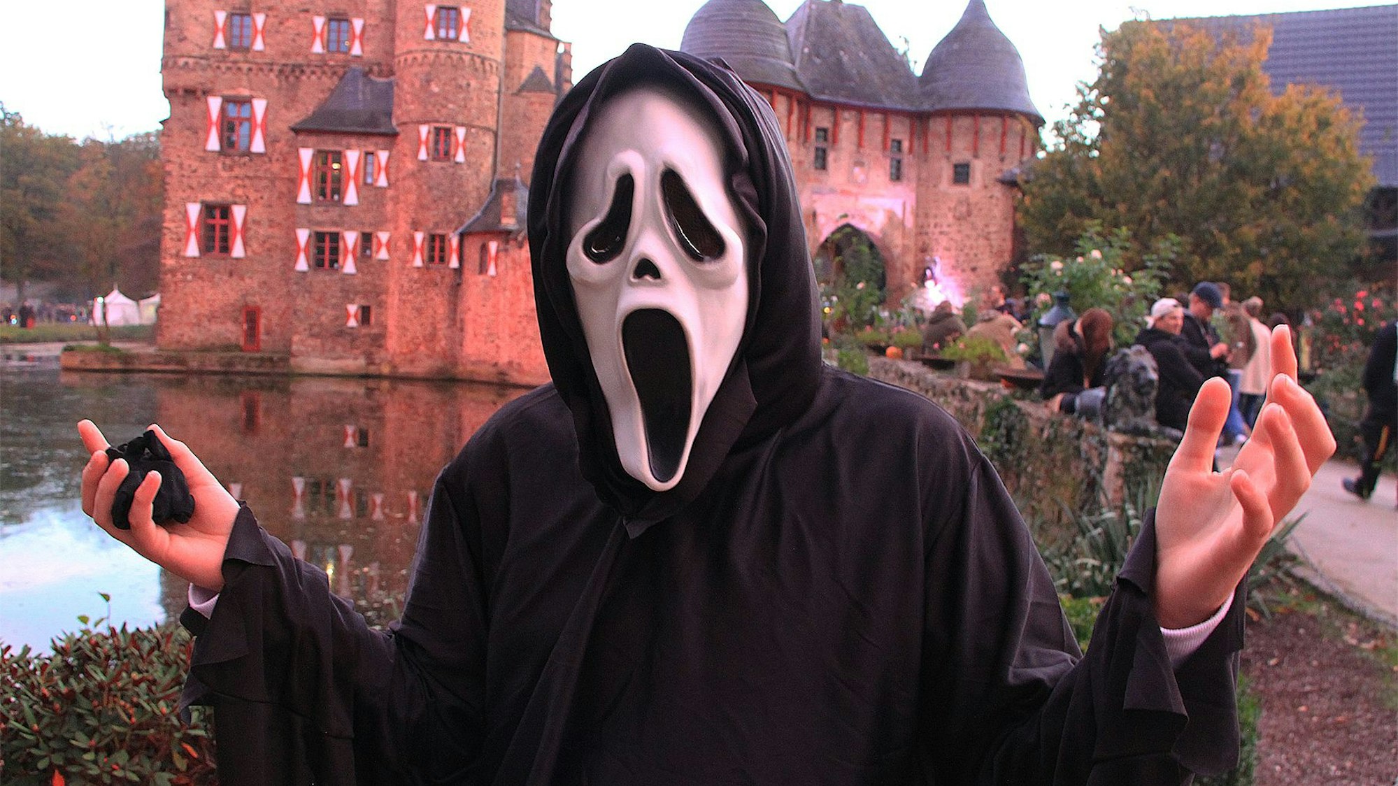 Eine Person in Scream-Maske steht vor der Burg Satzvey.