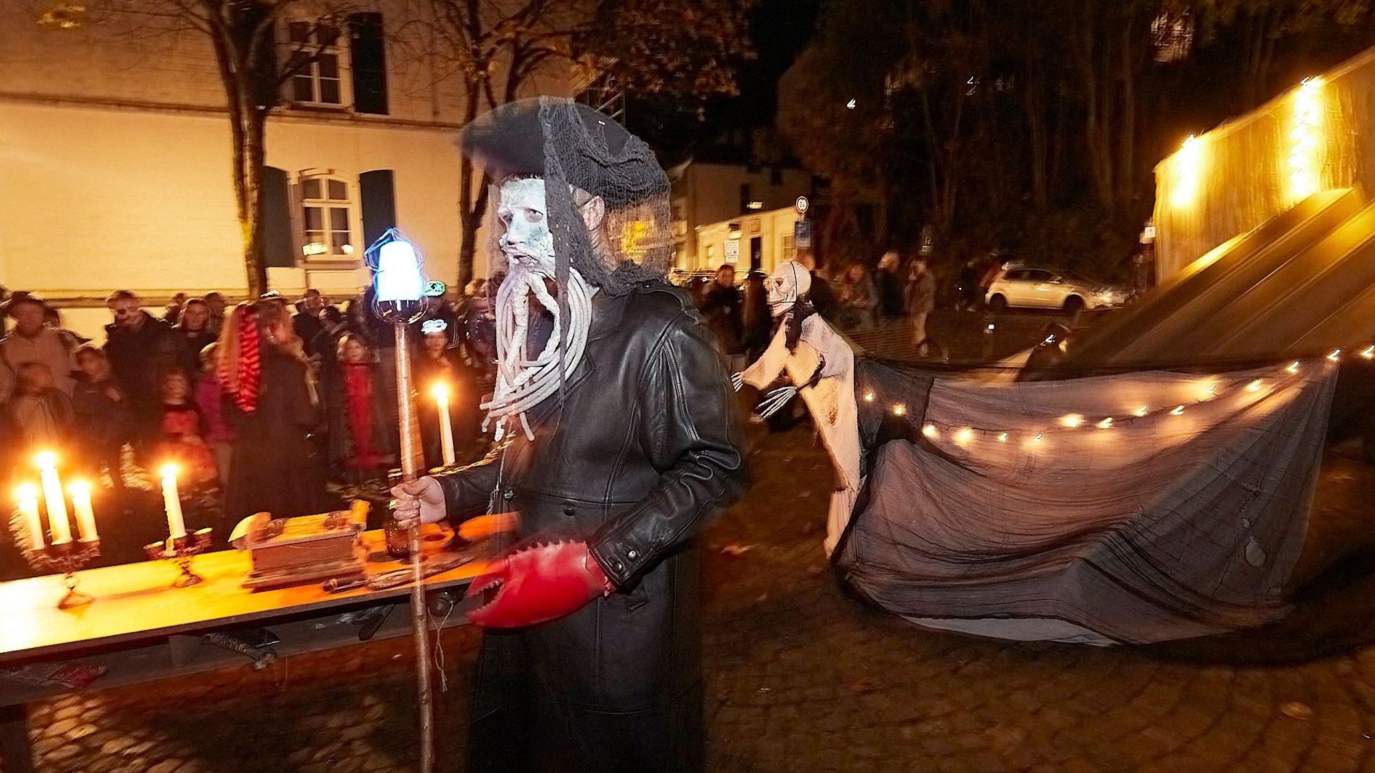 Kapitän Davy Jones, schwarz gekleidet und weiß geschminkt, schiebt einen Tisch mit Kerzen darauf durch die Straßen.