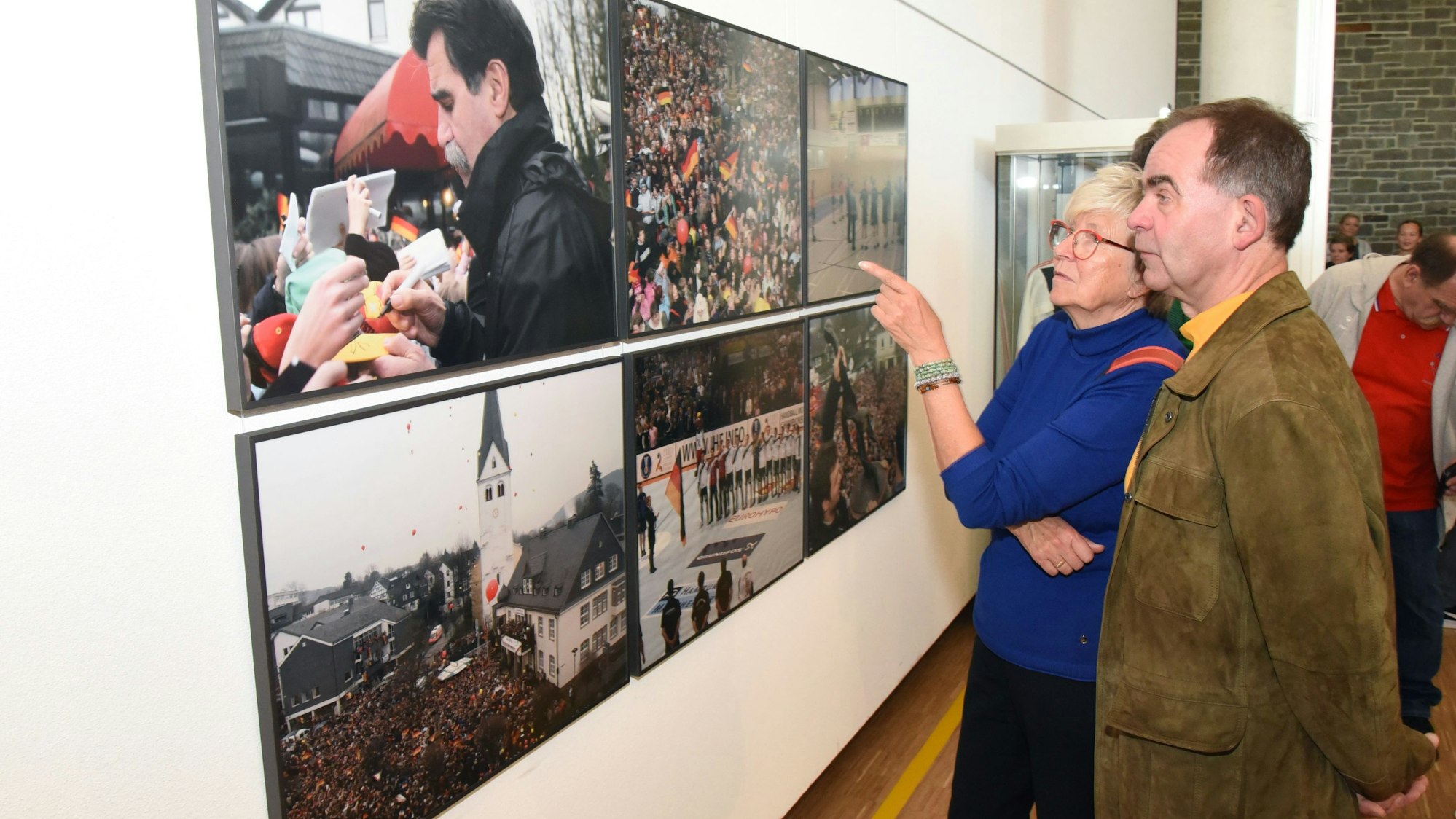 Eine Besucherin und ein Besucher unterhalten sich vor den Fotos mit den Menschenmassen in Wiehl.
