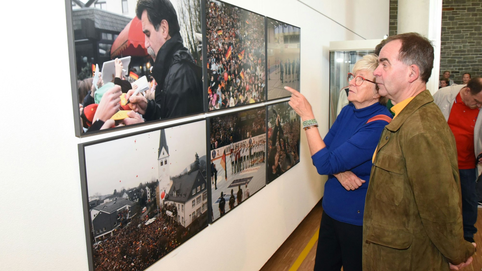 Eine Besucherin und ein Besucher unterhalten sich vor den Fotos mit den Menschenmassen in Wiehl.