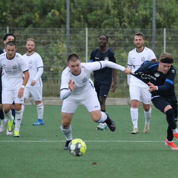 Ein Fußballspieler zieht seinem Gegenspieler beim Kampf um den Ball am Trikot.