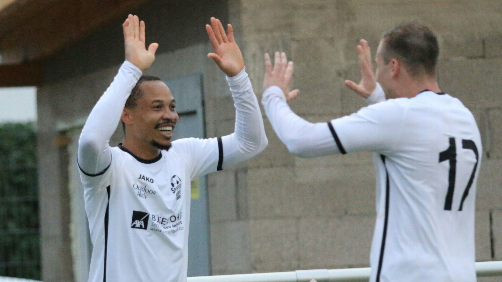 Ein Fußballer klatscht mit seinem Mitspieler ab.