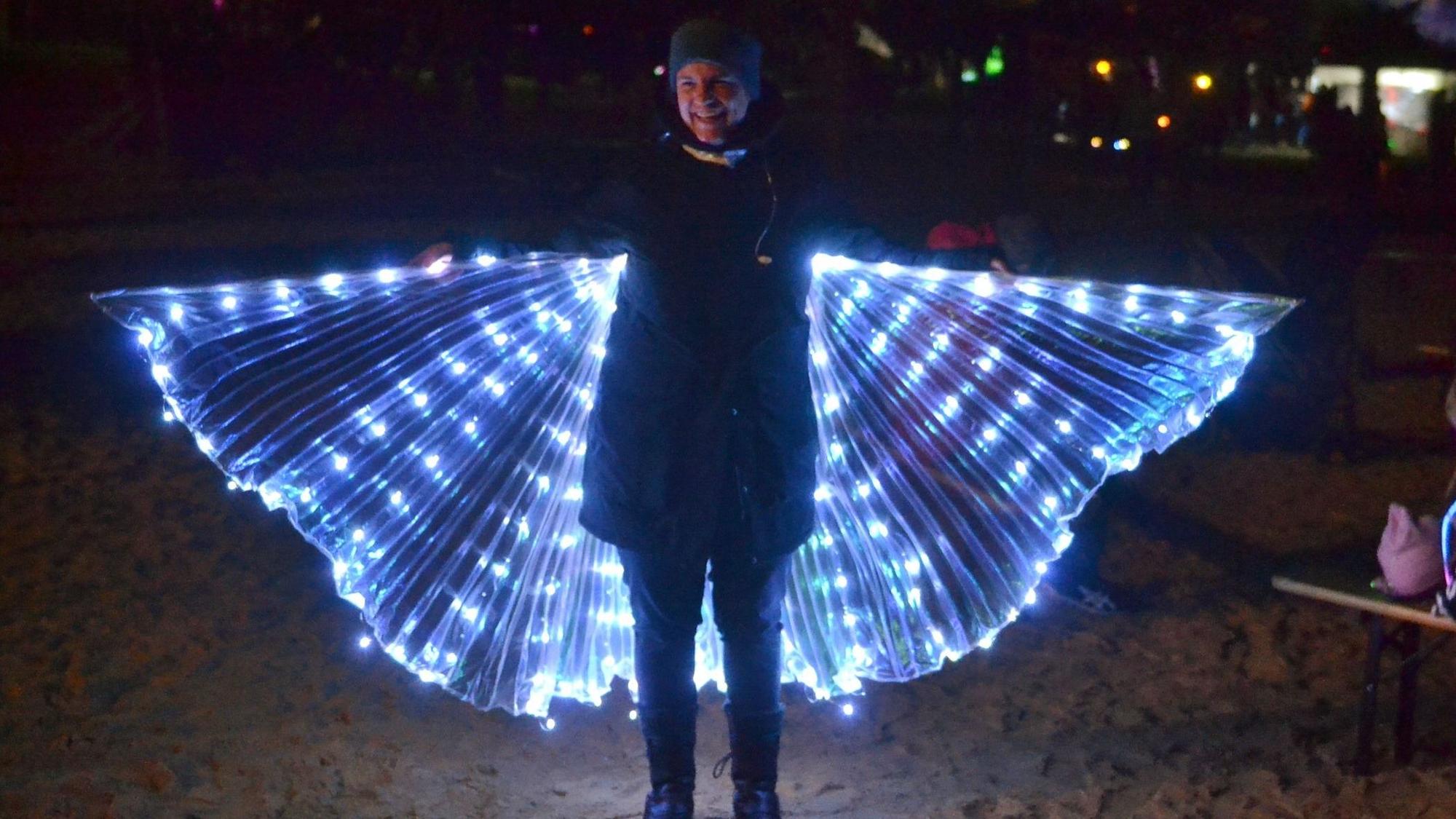 Das Bild zeigt Besucherin Anja, die ihre beleuchteten Flügel spannte.
