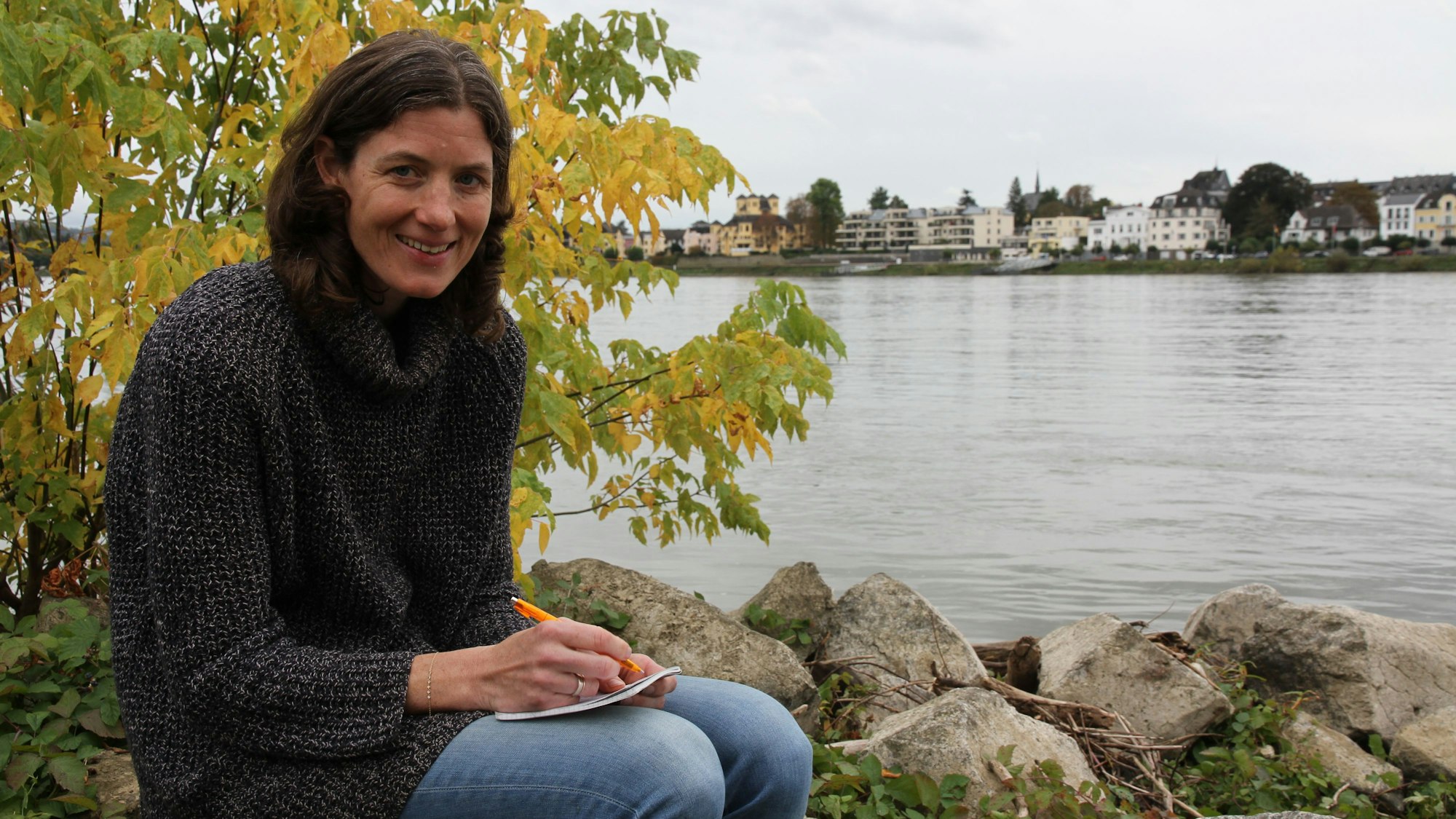 Eine Frau mit Notizblock an einem Flussufer