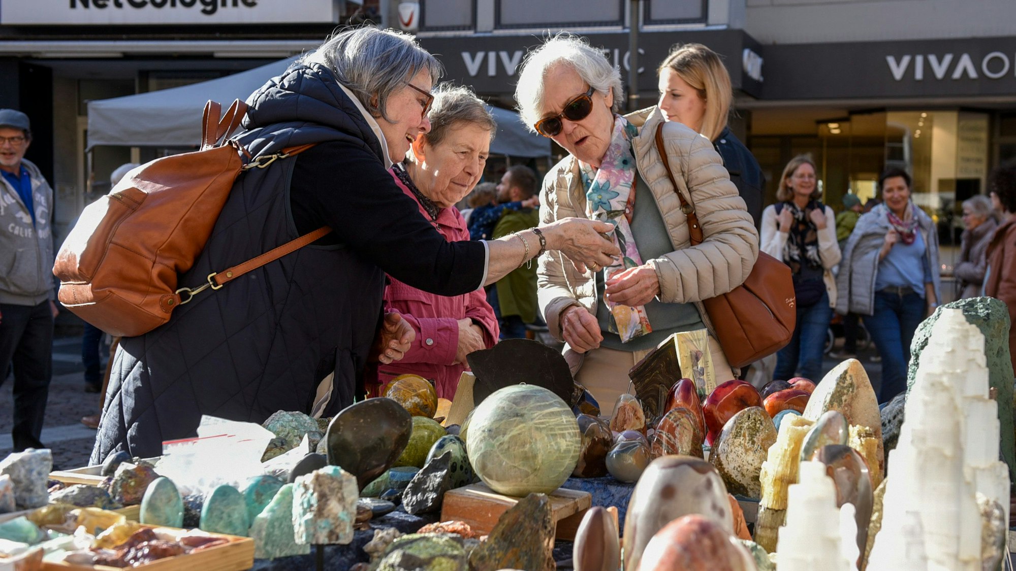 Drei ältere Damen schauen sich das Angebot am Stand an.