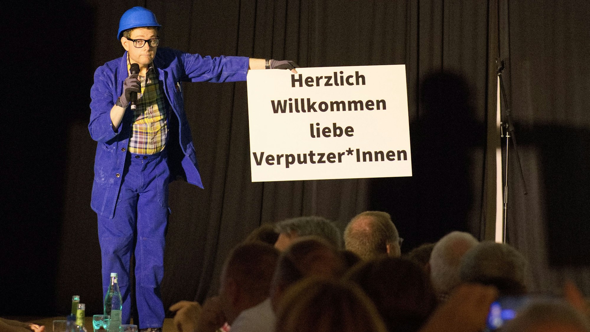 Das Bild zeigt Kai Kramosta als Handwerker verkleidet auf der Bühne.