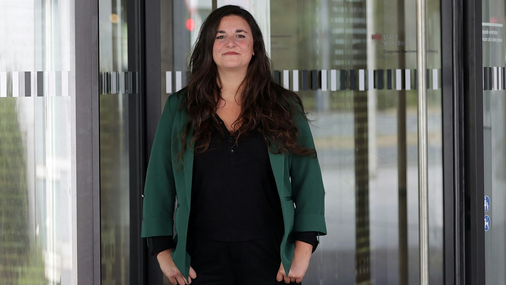 Eine Frau steht vor einer Glastür.