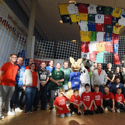 In einem Netz ist das große Trikot befestigt. Davor haben sich die Besucher der Ausstellung platziert.