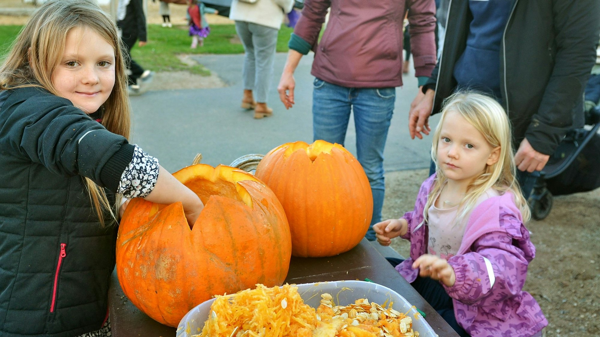 Das Bild zeigt die beiden Kinder beim Aushöhlen von Kürbissen.