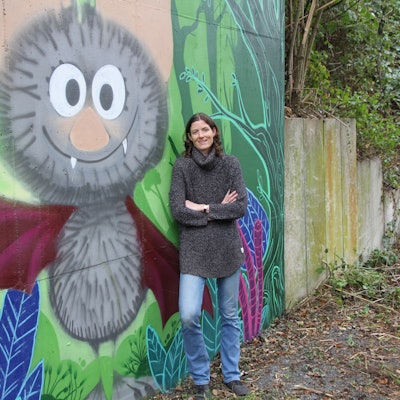 Eine Frau vor einem Graffiti mit einer Fledermaus.
