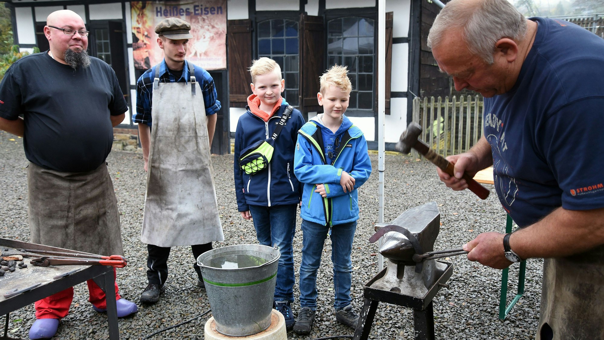 Am Amboss zeigt ein Schmiedemeister, wie mit vielen Hammerschlägen ein Hufeisen entsteht.