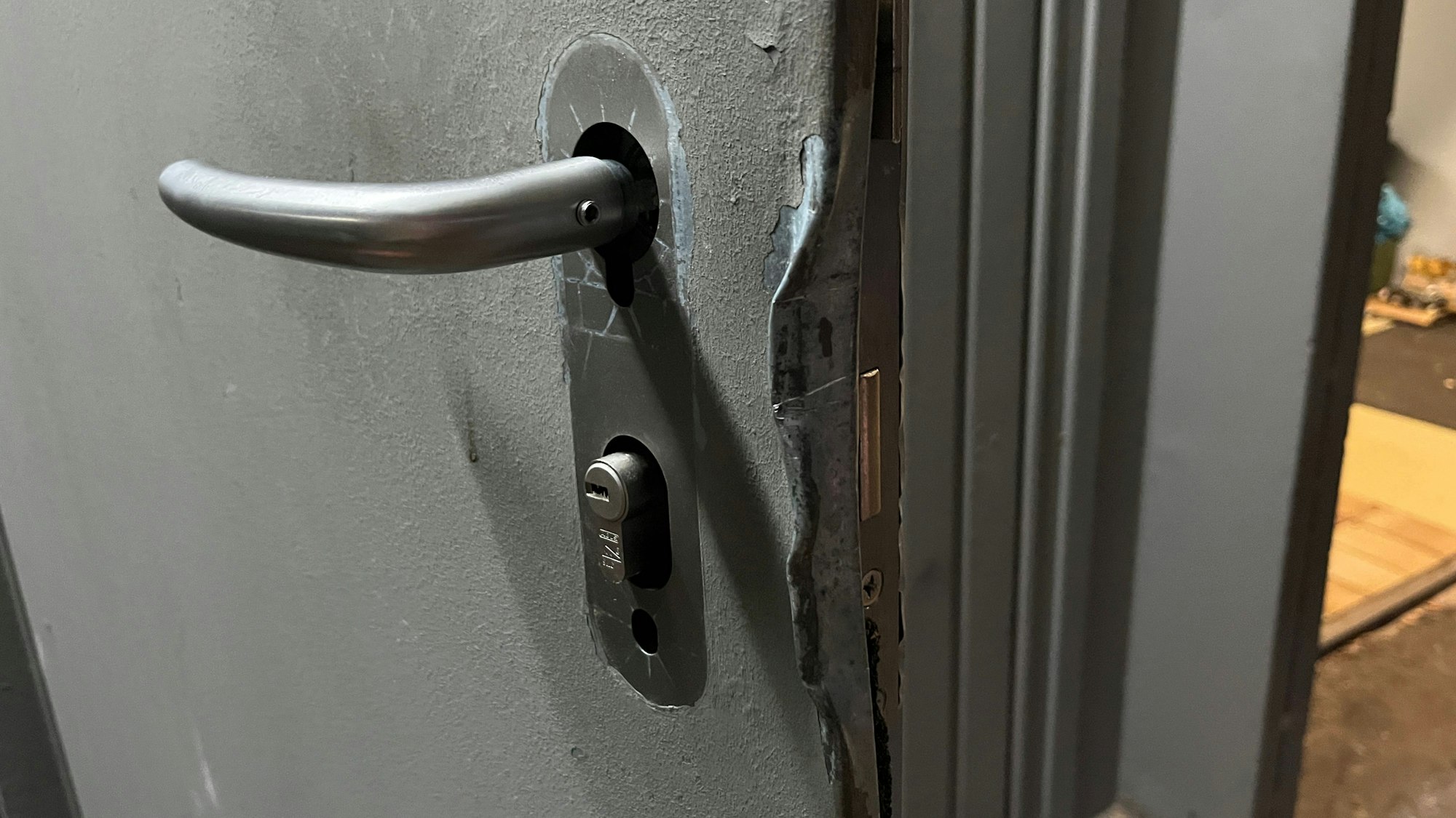 An einer Tür ist ein verbogenes Türschloss zu sehen.