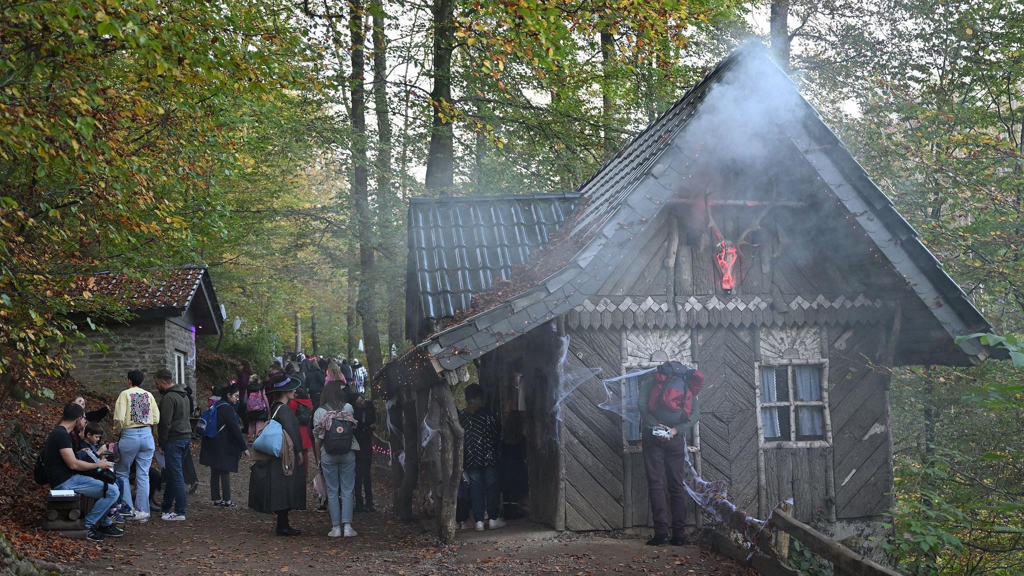 Nebel steigt an einem Haus im Altenberger Märchenwald auf, davor stehen Menschen.