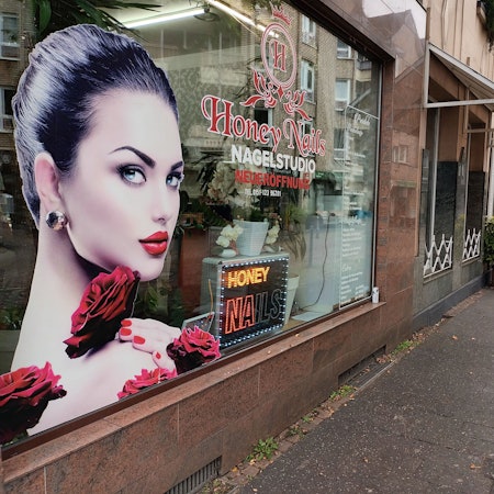 Ein Schaufenster eines Nagelstudios neben einem alteingesessenen Polstereibetrieb