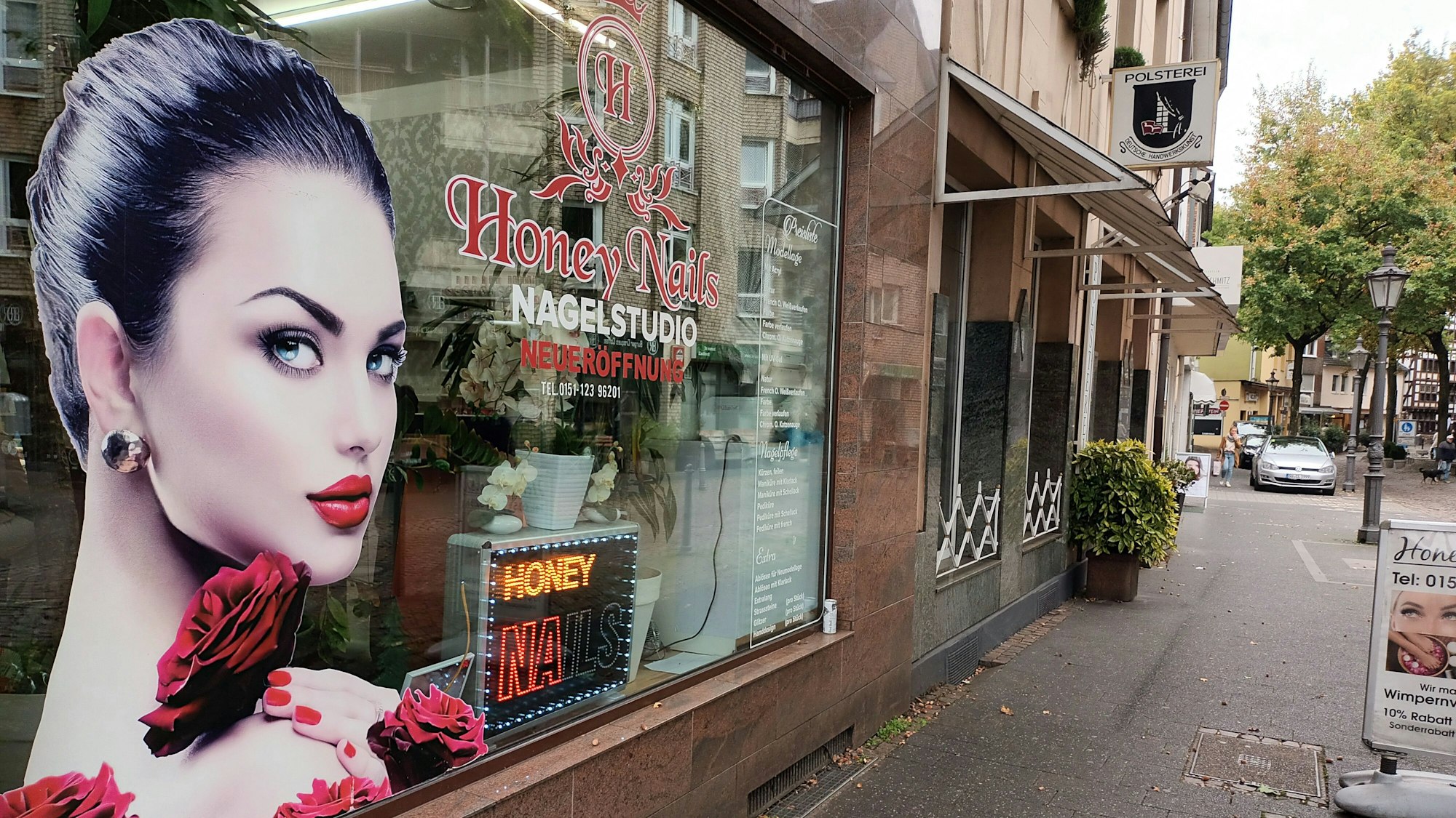 Ein Schaufenster eines Nagelstudios neben einem alteingesessenen Polstereibetrieb