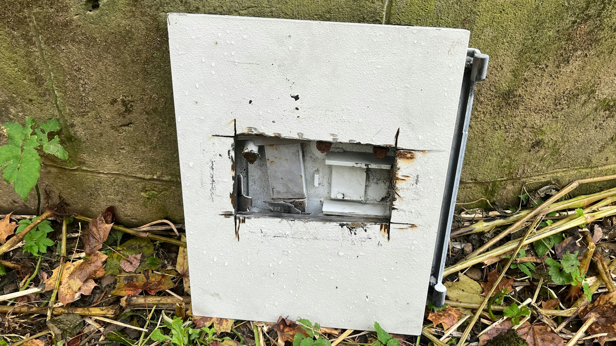 Eine Tresortür steht vor einer Betonwand.