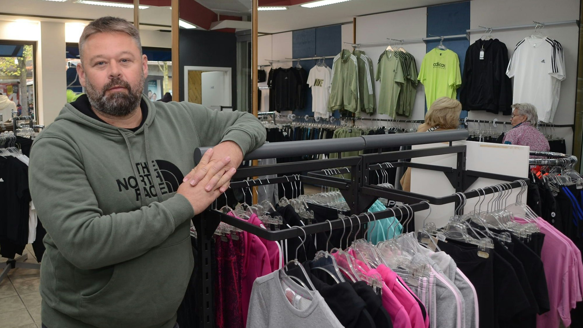 Ein Mann steht in einem Geschäft an einem Kleiderständer