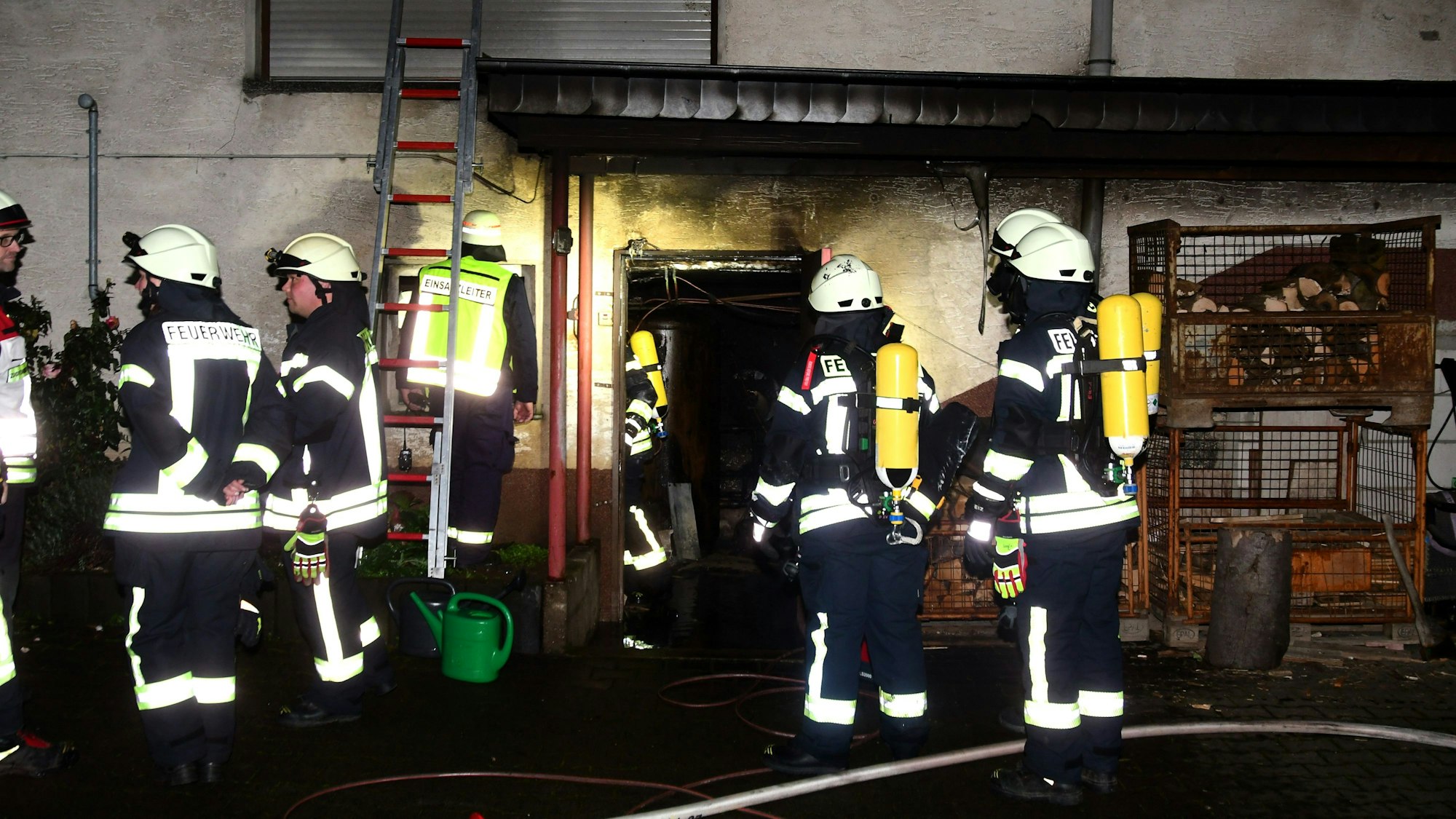Das Bild zeigt zahlreiche Feuerwehrleute, die vor dem Einfamilienhaus stehen.