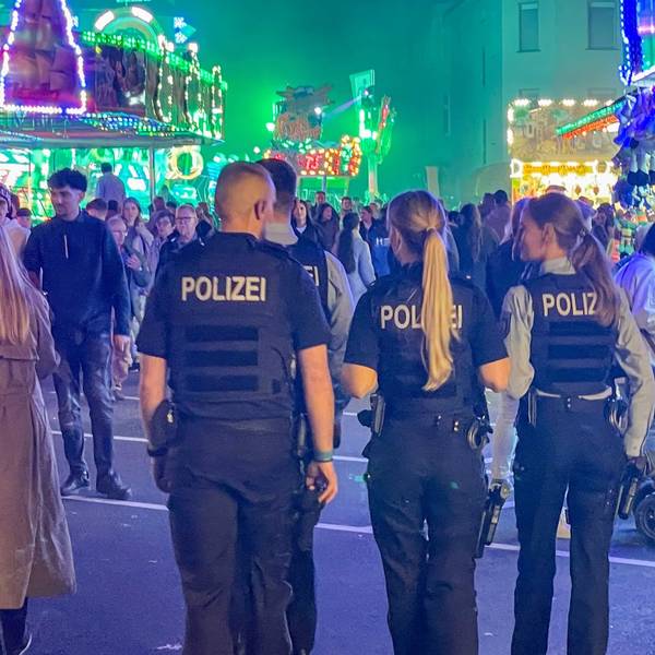 Das Bild zeigt vier Polizeibeamte, die über den Kirmesparcours gehen.