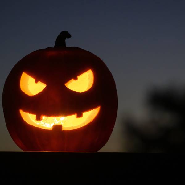 Ein ausgehöhlter, leuchtender Kürbis mit einem geschnitzten grinsenden Gesicht schmückt an Halloween viele Haushalte