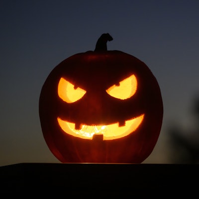 Ein ausgehöhlter, leuchtender Kürbis mit einem geschnitzten grinsenden Gesicht schmückt an Halloween viele Haushalte