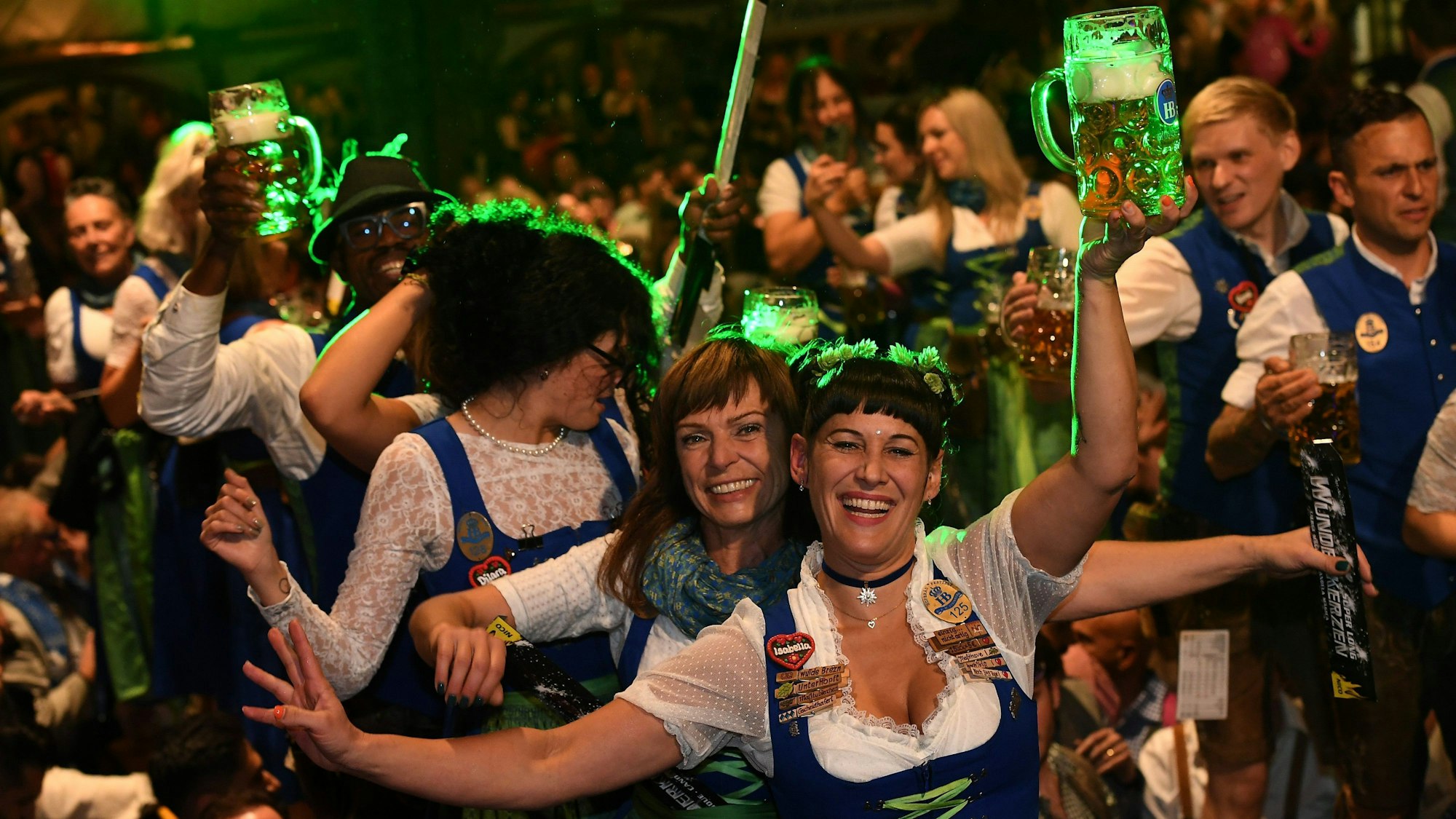 Feiernde Menschen in Dirndl und Lederhosen und mit Bierkrügen