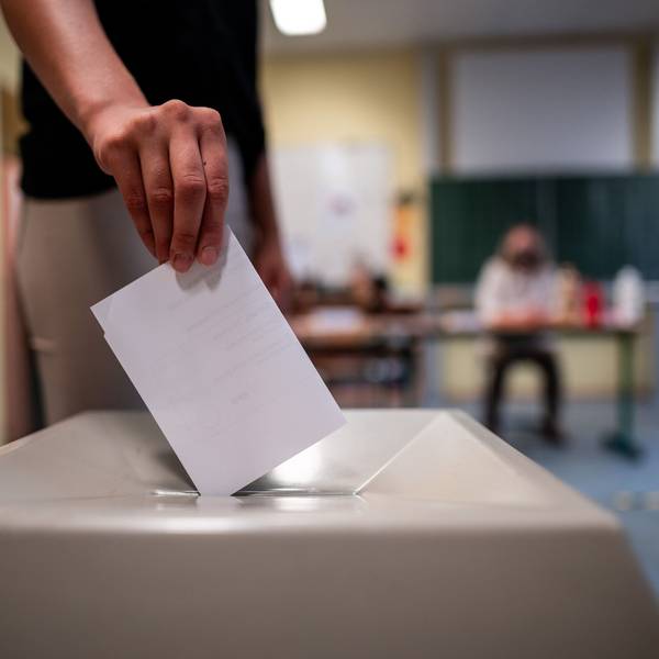 Eine Frau wirft einen Wahlschein in eine Wahlurne.