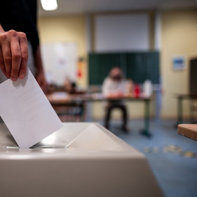 Eine Frau wirft einen Wahlschein in eine Wahlurne.