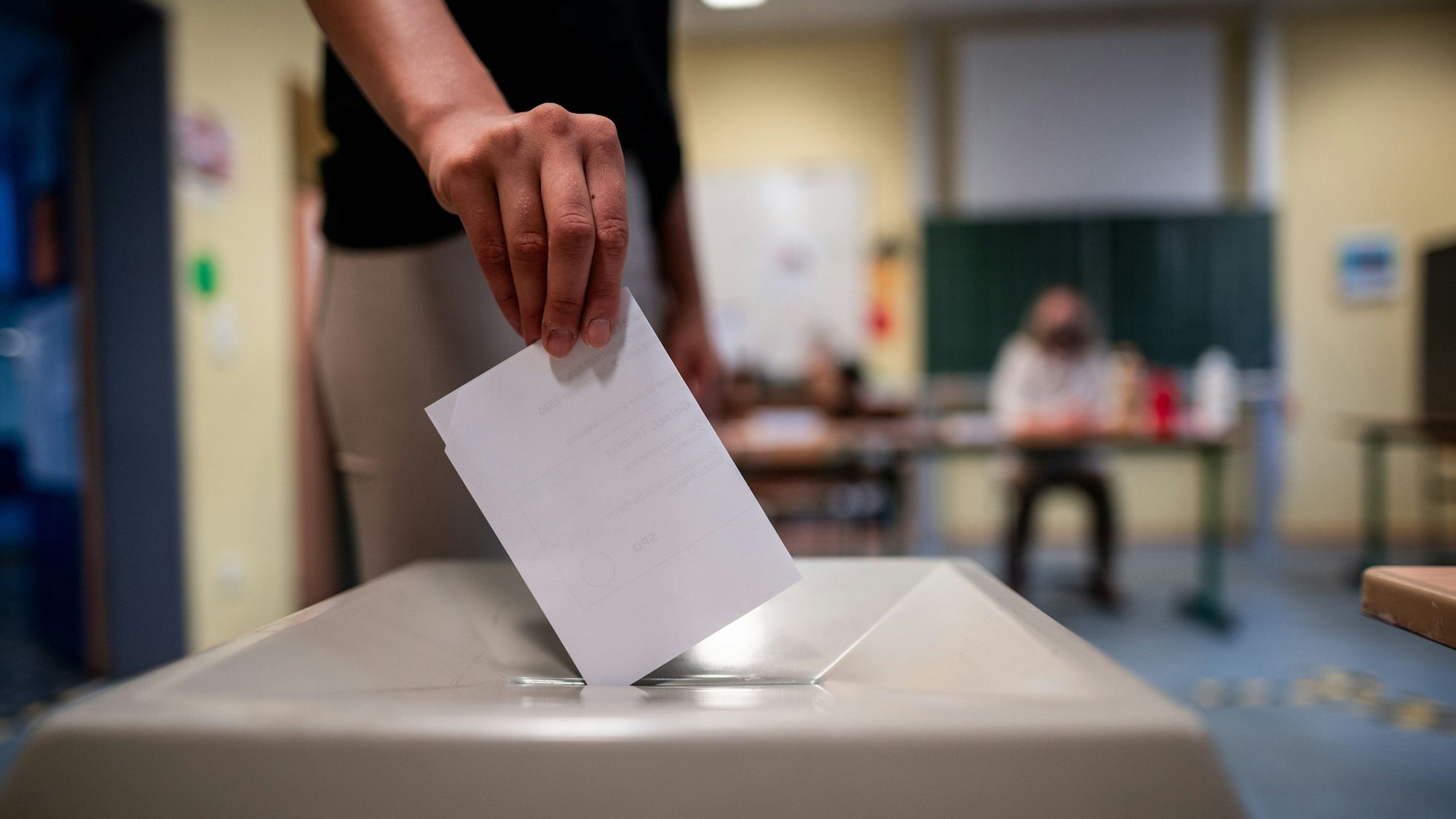 Eine Frau wirft einen Wahlschein in eine Wahlurne