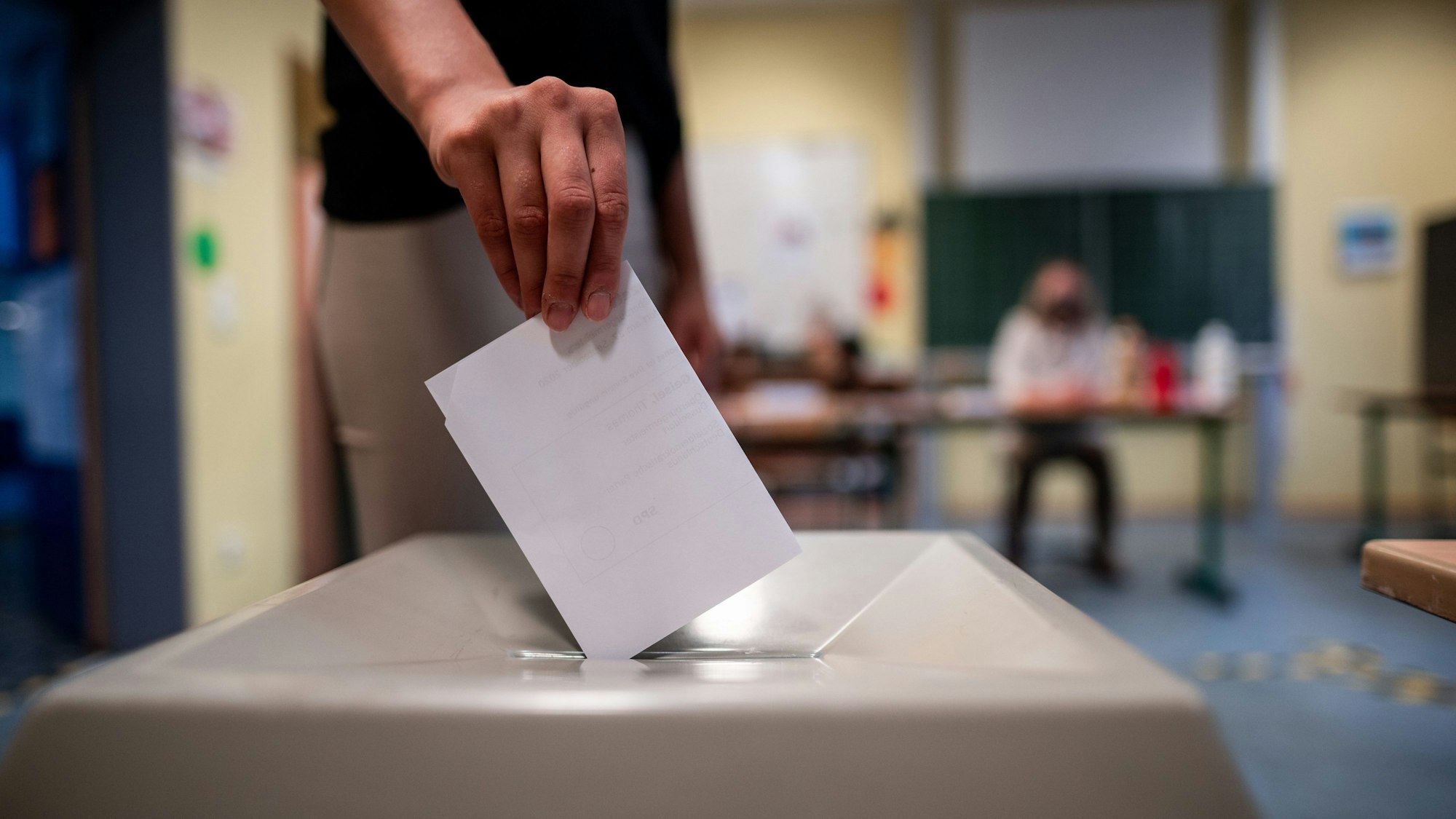 Eine Frau wirft einen Wahlschein in eine Wahlurne.