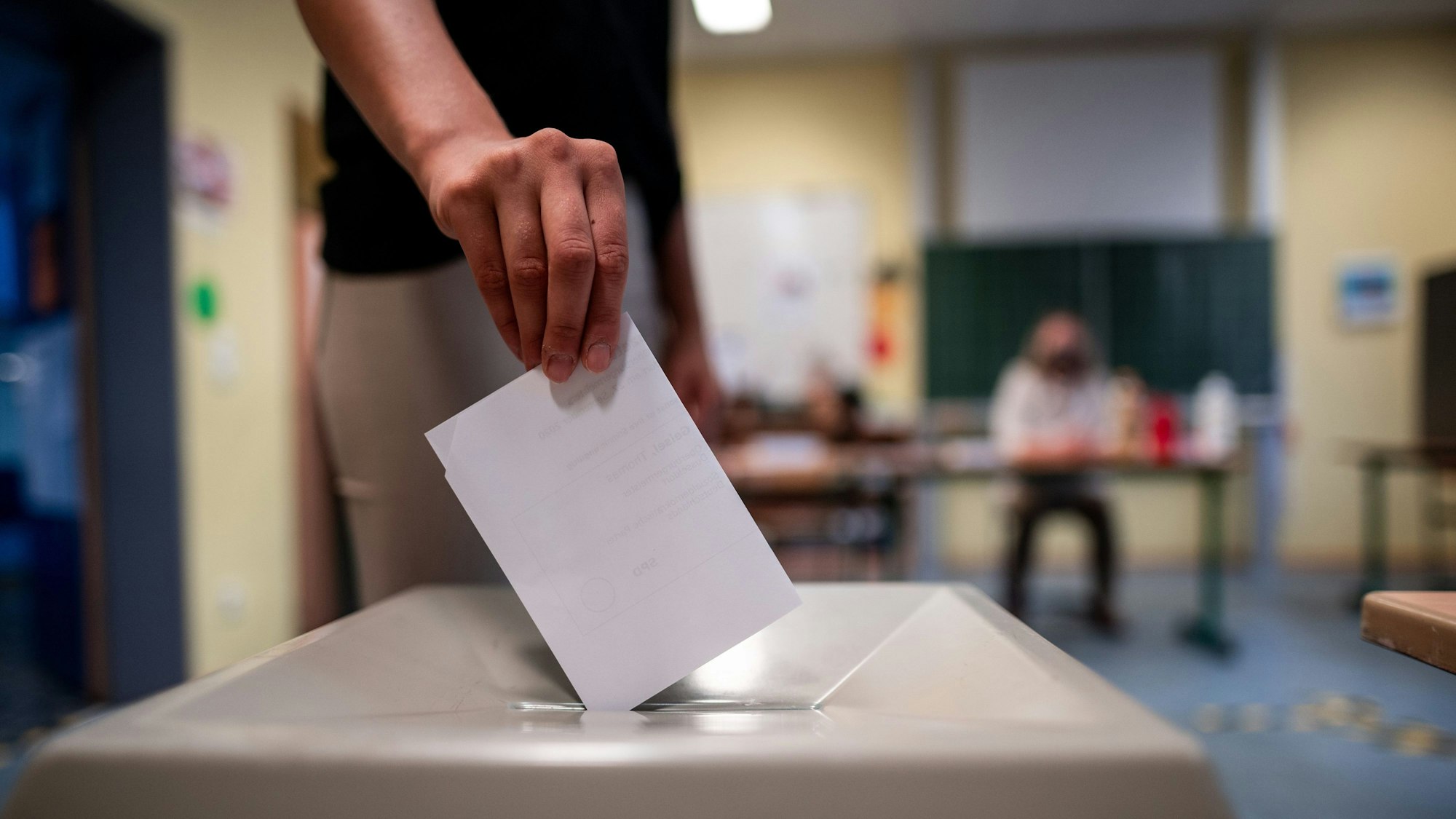 Eine Frau wirft einen Wahlschein in eine Wahlurne.