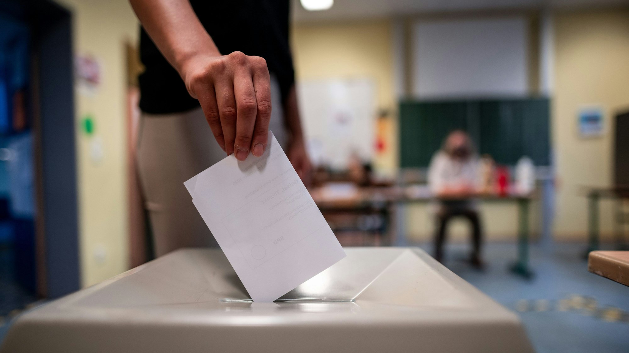 Eine Frau wirft einen Wahlschein in eine Wahlurne.