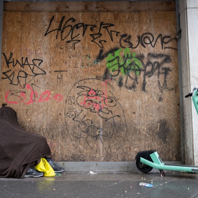 Vor strömendem Regen will sich ein obdachloser Mann schützen.