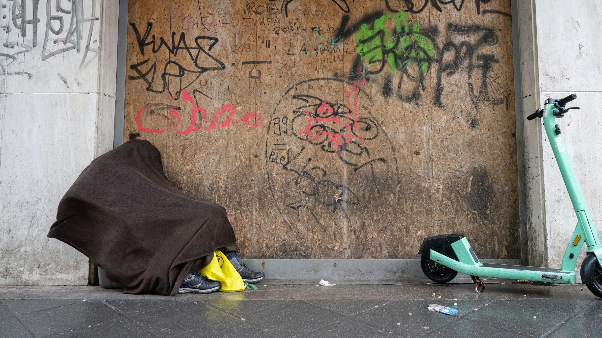 Vor strömendem Regen will sich ein obdachloser Mann schützen.