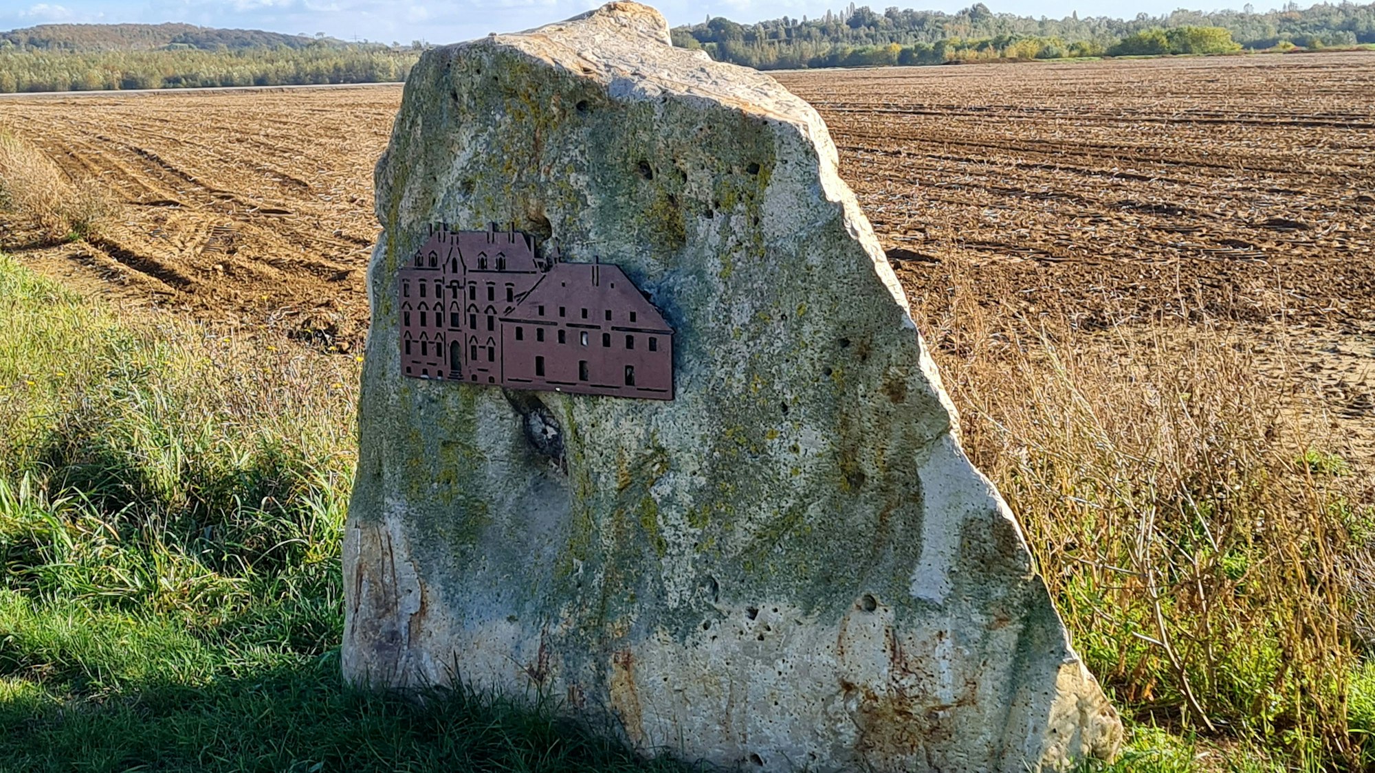 Das Abbild des Klosters ist auf einem großen Fels angebracht, der vor einem Feld steht.