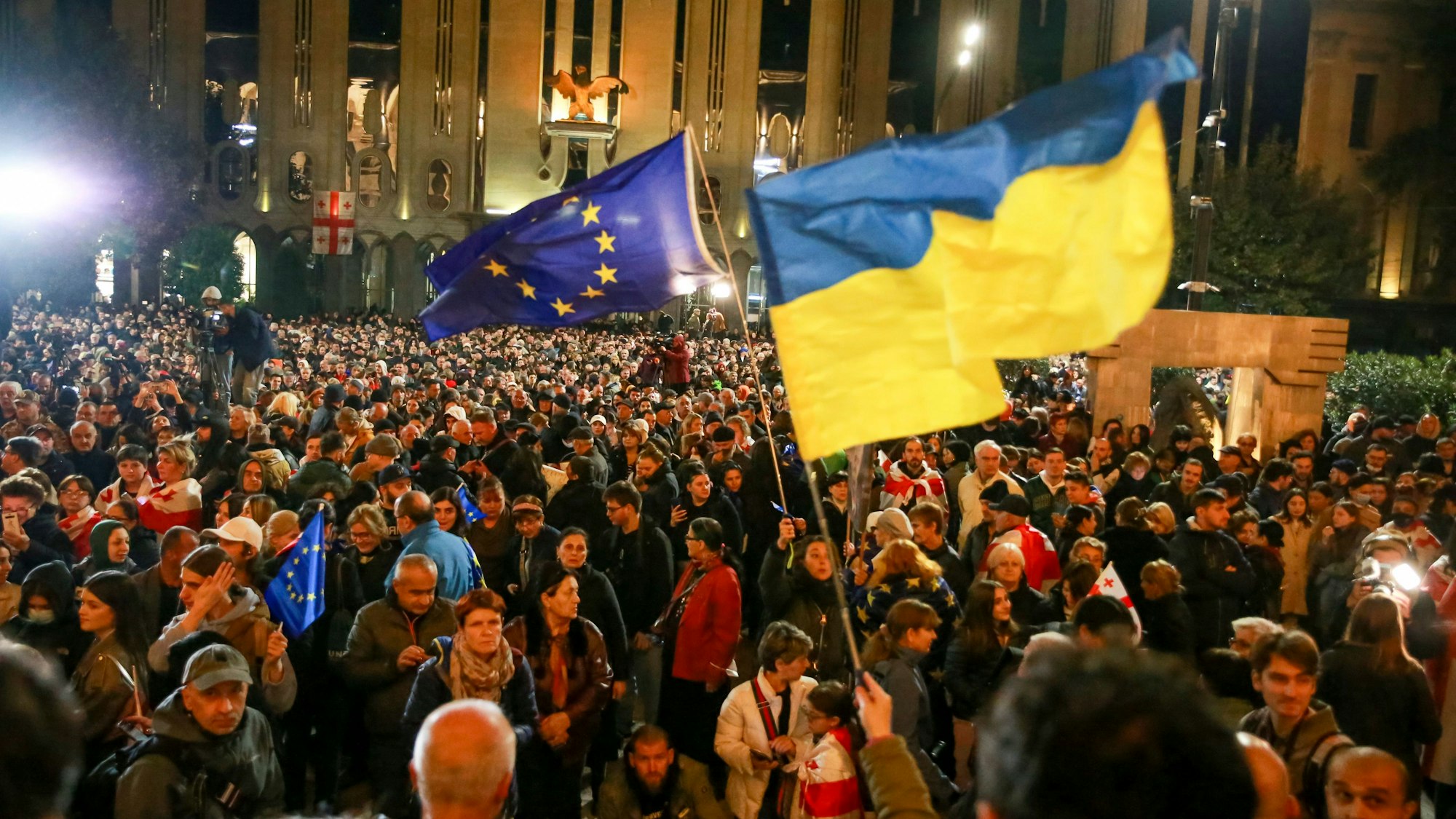 Demonstranten schwenken EU- und ukrainische Nationalflaggen, als sie sich während eines Protestes der Opposition gegen die Ergebnisse der Parlamentswahlen in Georgien versammeln.