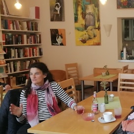 Eine Frau sitzt im Café an einem Tisch, sie unterhält sich.