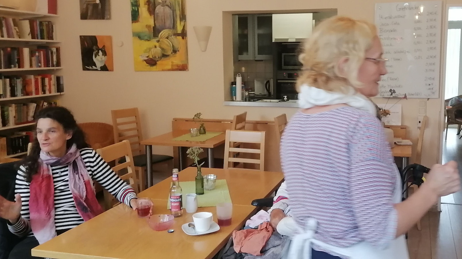 Eine Frau sitzt im Café an einem Tisch, sie unterhält sich.