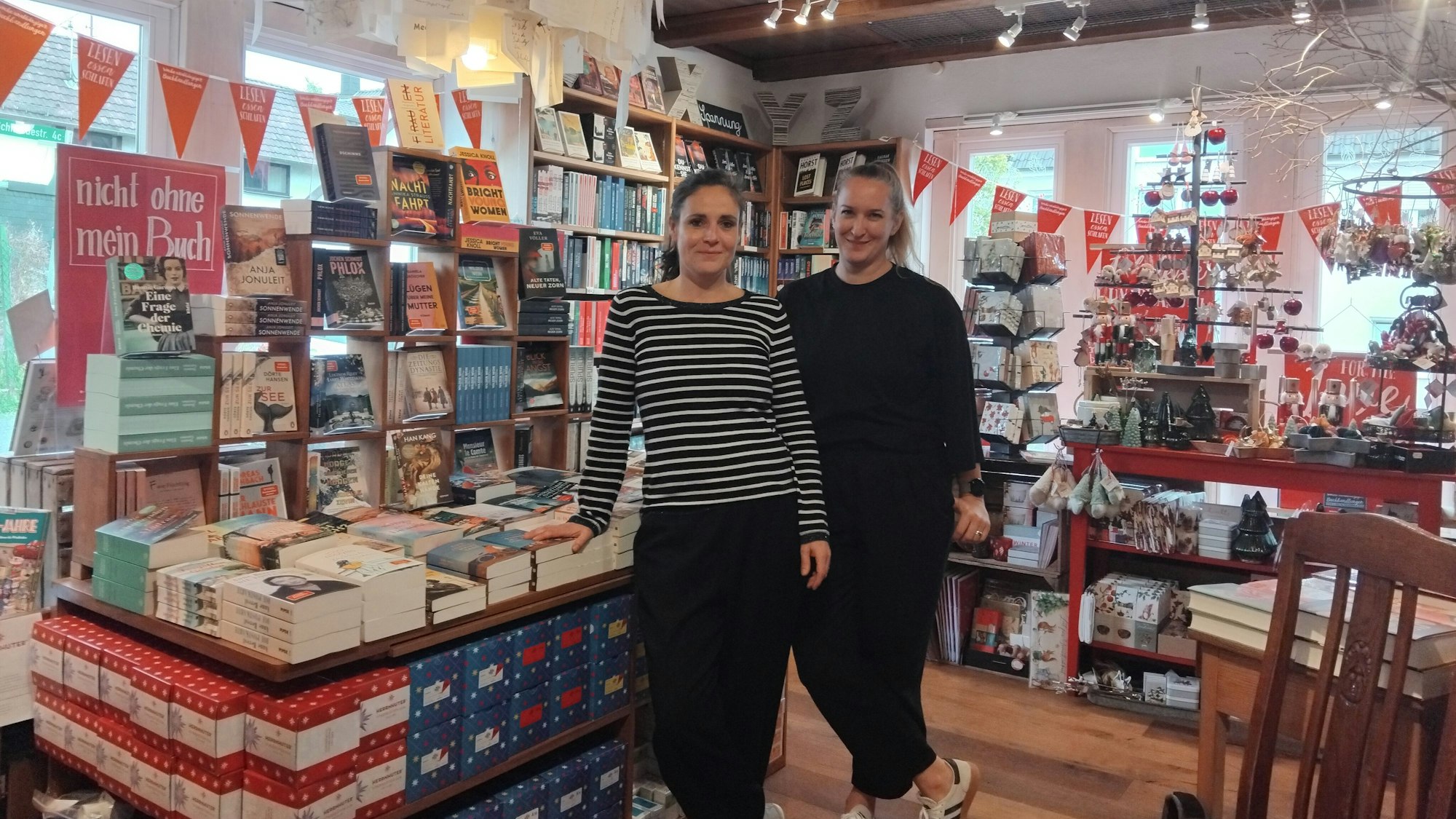 Zwei Frauen stehen in einer weihnachtlich dekorierten Buchhandlung.