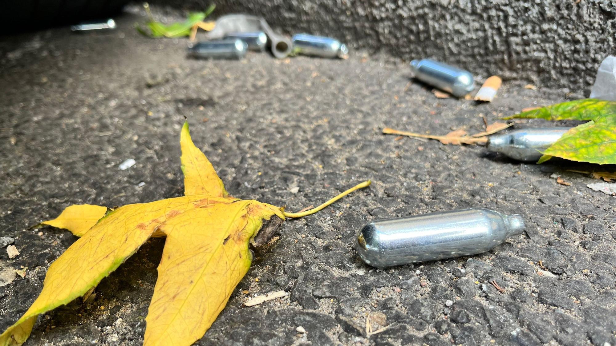 Auf einer Straße liegen mehrere Gaspatronen mit Lachgas.